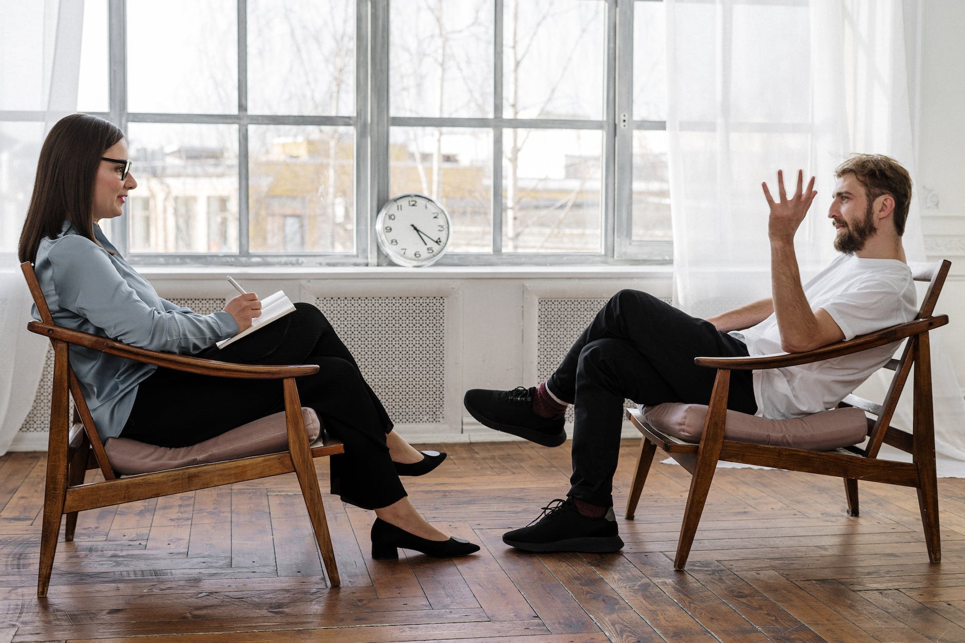 person in black pants and black shoes sitting on brown wooden chair